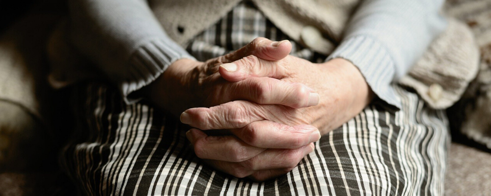 older woman sitting with hands folded in her lap - Jake's Diapers provides incontinence help for seniors